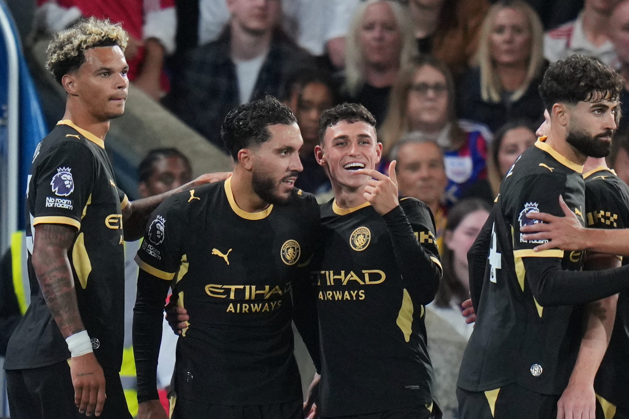 Manchester City players celebrate together after scoring, with Phil Foden